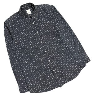 May include: A long-sleeve button-down shirt in dark charcoal gray featuring an all-over repeating pattern of small white bird silhouettes. The shirt includes a standard collar, a front button placket, and a label reading AAR at the neckline.