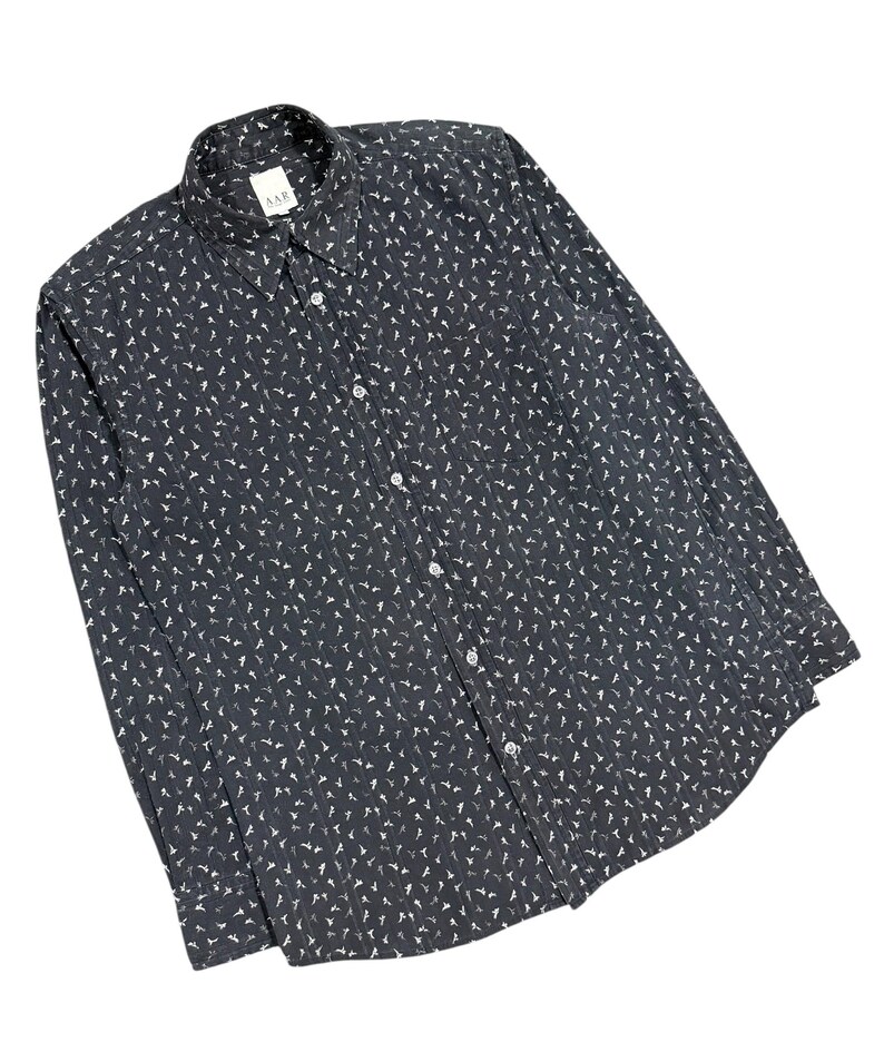 May include: A long-sleeve button-down shirt in dark charcoal gray featuring an all-over repeating pattern of small white bird silhouettes. The shirt includes a standard collar, a front button placket, and a label reading AAR at the neckline.