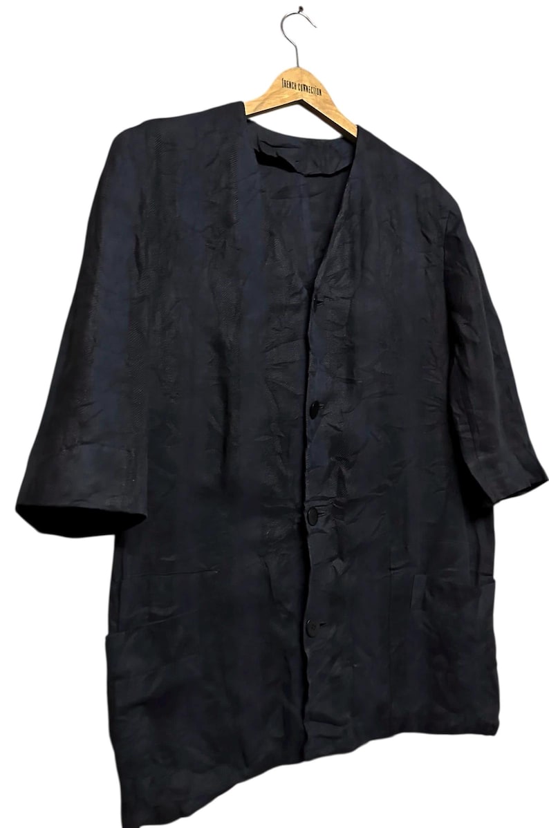 May include: A dark navy blue button-down shirt with a subtle tonal textured pattern, featuring a V-neckline, three-quarter length sleeves, and two front patch pockets. The garment is displayed on a wooden hanger labeled French Connection.