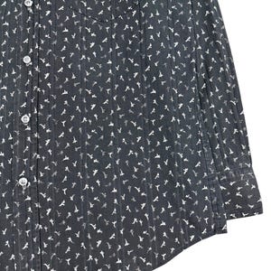 May include: A dark gray long-sleeve button-down shirt featuring a repeating white floral pattern and vertical pinstripes. The garment includes a front chest pocket, a standard collar, and light-colored buttons running down the front placket.