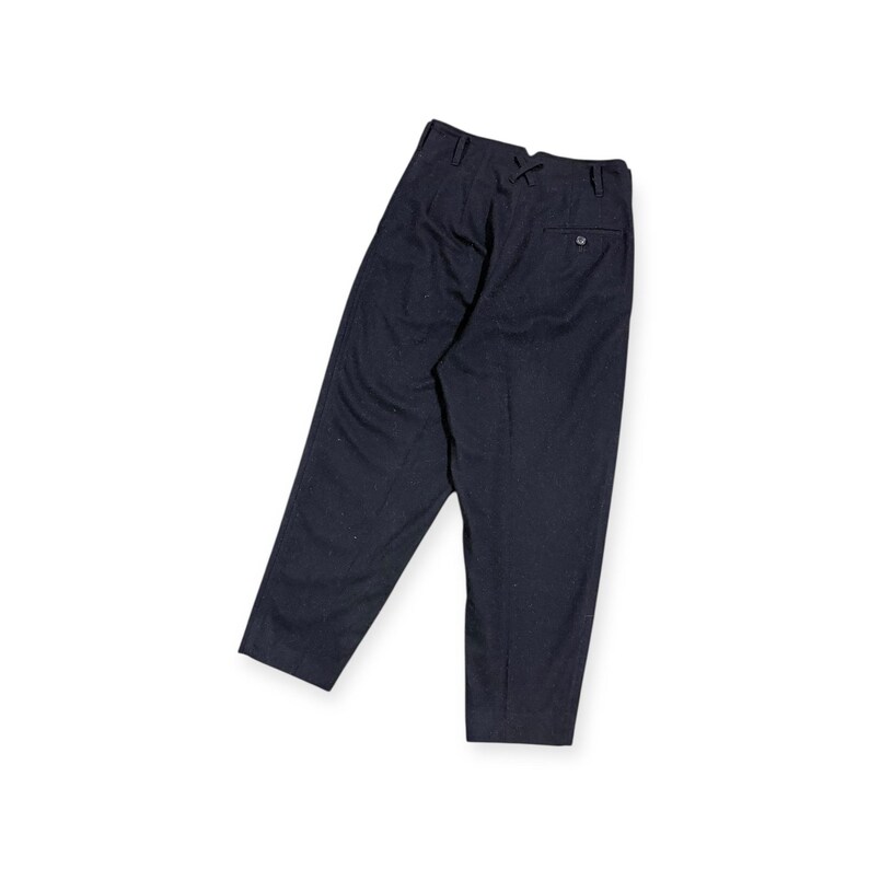 Puede incluir: Un pantal&oacute;n azul marino oscuro con dise&ntilde;o de cintura alta, trabillas para cintur&oacute;n, un bolsillo trasero con bot&oacute;n y un peque&ntilde;o detalle decorativo de punto de cruz situado en el centro de la cinturilla. El pantal&oacute;n tiene corte c&oacute;nico.