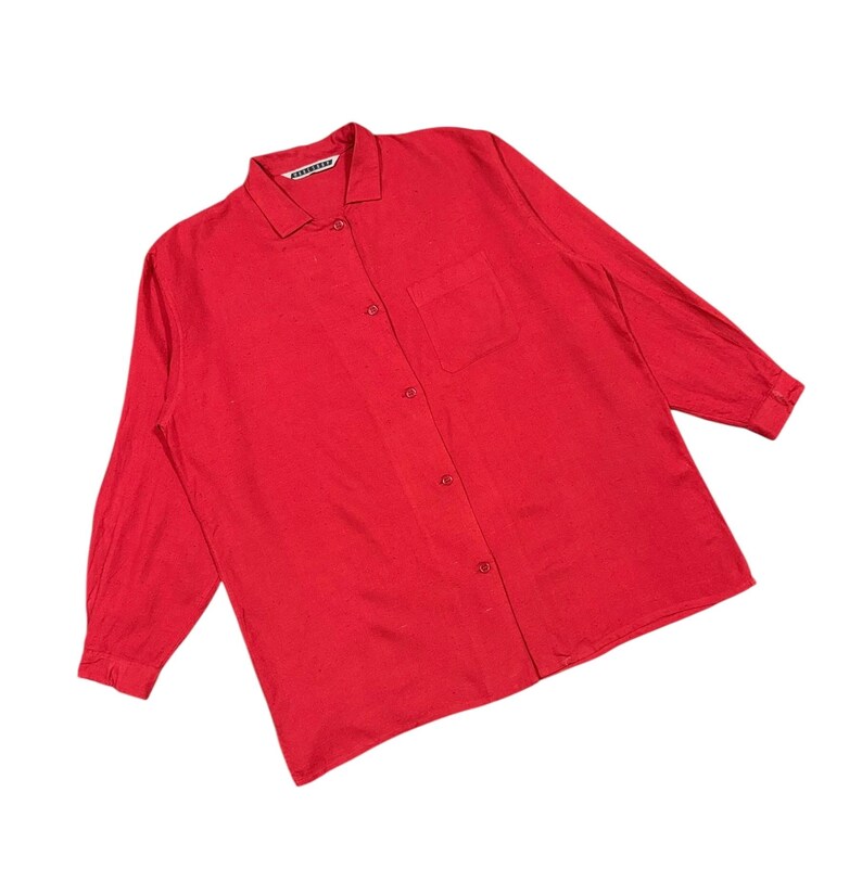 Puede incluir: Camisa roja brillante de manga larga con botones, cuello y un bolsillo en el pecho. La camisa tiene un dise&ntilde;o cl&aacute;sico y est&aacute; hecha de una tela suave. El nombre de la marca es visible en el cuello.