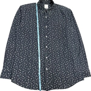 May include: A dark gray long-sleeve button-down shirt with a white repeating pattern of small figures. A blue measuring tape is placed vertically along the center, showing a length of approximately 30 inches from the collar to the bottom hem.