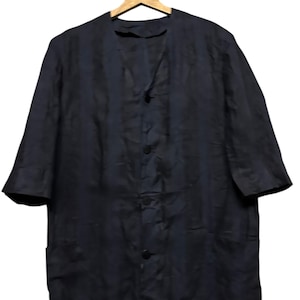 May include: A dark navy blue button-down shirt with a subtle vertical striped pattern, featuring a collarless V-neckline, three-quarter length sleeves, and two front pockets, displayed on a wooden hanger against a plain background.