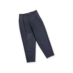 Puede incluir: Un pantal&oacute;n de color gris carb&oacute;n oscuro con dise&ntilde;o de cintura alta, pliegues frontales, cierre de un solo bot&oacute;n en la pretina, trabillas para cintur&oacute;n y silueta de pierna c&oacute;nica. La tela presenta una apariencia sutilmente texturizada.