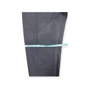 Puede incluir: Un pantal&oacute;n de color gris carb&oacute;n oscuro con corte recto. Una cinta m&eacute;trica de color azul claro est&aacute; colocada horizontalmente sobre la tela, indicando una medida de ancho de aproximadamente 28 cm en este punto espec&iacute;fico de la prenda.