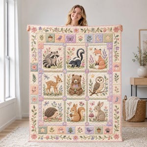 Op de afbeelding: Een rechthoekige quilt met een raster van negen panelen, elk met een ander bosdier zoals een wasbeer, stinkdier, vos, hert, beer, uil, egel, eekhoorn en konijn, omringd door een bloemenrand met zachte pastelkleurige accenten.
