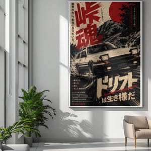 Könnte beinhalten: Ein vertikales Wandposter mit einem weißen und schwarzen Sportwagen, der auf einer Bergstraße driftet. Das Kunstwerk enthält eine große rote Sonne, japanische Kanji-Schriftzeichen und stilisierten Text in einem kontrastreichen Design.