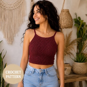 Könnte beinhalten: Ein weinrotes gehäkeltes Crop-Top mit dünnen Trägern. Das Top wird mit hellblauen Jeans getragen. Das Bild enthält den Text "CROCHET PATTERN" in einem beigen Kreis. Der Hintergrund umfasst dekorative Wandbehänge und Pflanzen.