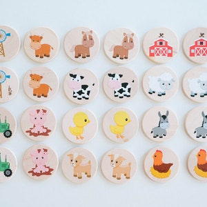 May include: Wooden farm animal matching game featuring illustrations of a windmill, cow, horse, barn, sheep, pig, chick, donkey, goat, tractor, and chicken. The game pieces are round and have a light wood finish.