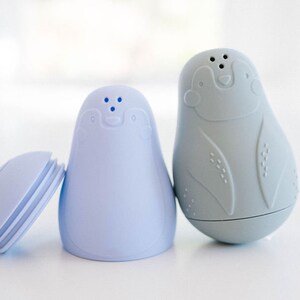 May include: Two ceramic salt and pepper shakers shaped like penguins. The salt shaker is light blue and the pepper shaker is light gray.
