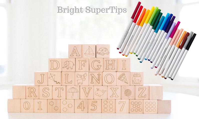 May include: Wooden alphabet blocks with etched letters, numbers, and illustrations, stacked in a pyramid. A set of colorful markers with white barrels and colored tips are arranged diagonally. The text "Bright SuperTips" is at the top.