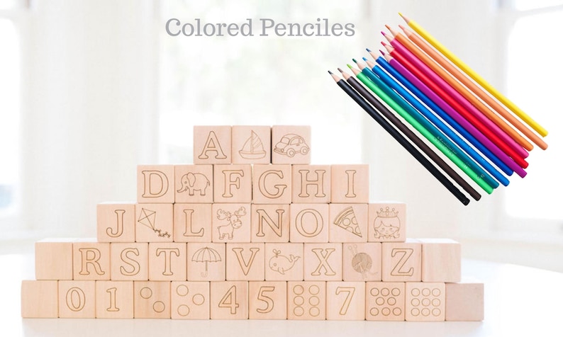 May include: Wooden alphabet blocks with etched letters and illustrations, stacked in a pyramid shape. A set of colored pencils in various colors is positioned to the right. The text "Colored Pencils" is at the top.