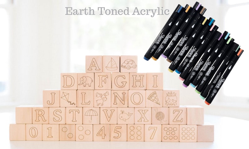 May include: Wooden alphabet blocks with etched letters and illustrations, stacked in a pyramid. The blocks are accompanied by a set of colorful Sharpie markers. The text "Earth Toned Acrylic" is at the top.
