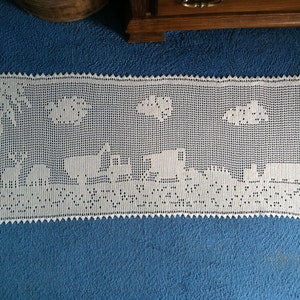 Puede incluir: Un camino de mesa de crochet blanco con un borde festoneado y un diseño de nubes y animales.