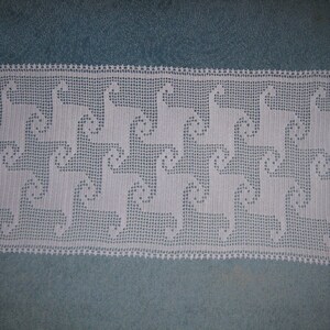 Puede incluir: Un camino de mesa blanco de ganchillo con un patrón repetido de llamas estilizadas. El camino de mesa está hecho de ganchillo delicado y calado y presenta un diseño simple y elegante.