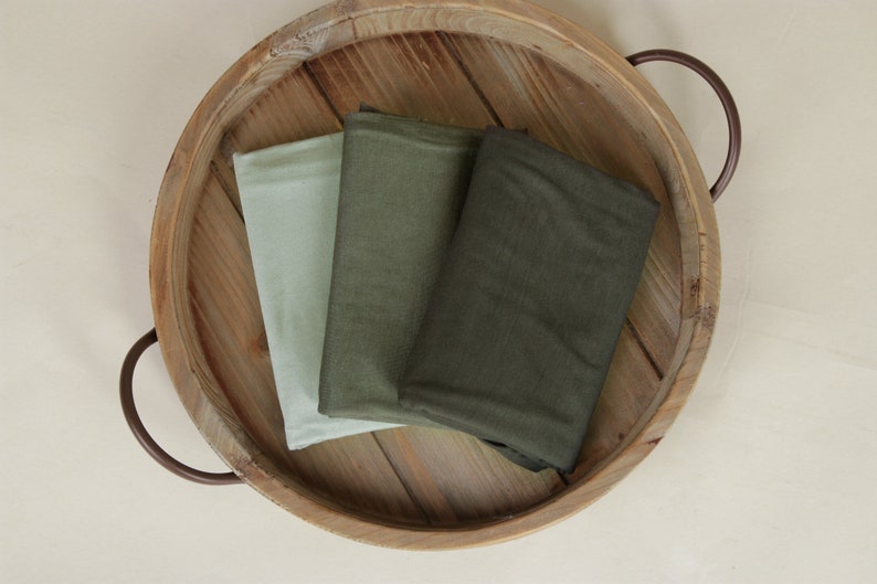 May include: Three fabric swatches in a wooden tray. The swatches are in shades of green and light green.