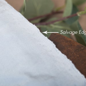May include: A close-up of a light blue fabric with a raw, unfinished edge labeled "Salvage Edge".