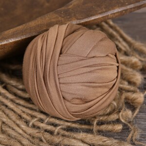 May include: A brown fabric roll for newborn photography. The roll is made of soft, stretchy fabric and is perfect for creating a variety of poses.