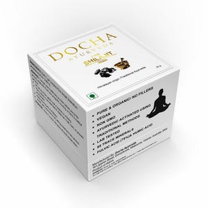 Op de afbeelding: Witte doos met gouden letters voor DOCHA Ayurveda Shilajit. De doos heeft een zwart silhouet van een mediterende persoon en vermeldt productkenmerken zoals veganistisch, niet-GMO en traditionele methoden.