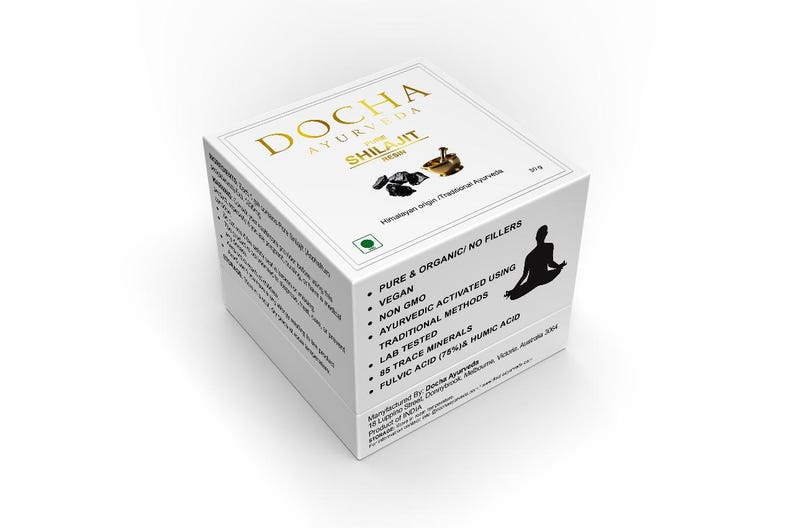 Op de afbeelding: Witte doos met gouden letters voor DOCHA Ayurveda Shilajit. De doos heeft een zwart silhouet van een mediterende persoon en vermeldt productkenmerken zoals veganistisch, niet-GMO en traditionele methoden.