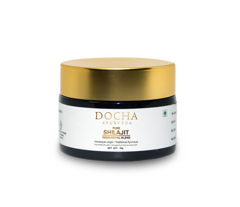 Op de afbeelding: Een kleine, ronde pot met een gouden deksel en een zwarte basis. Het etiket luidt "DOCHA AYURVEDA PURE SHILAJIT RESIN-ROYAL BLEND". De pot bevat een donkere substantie en is ge&euml;tiketteerd met een nettogewicht van 30g.