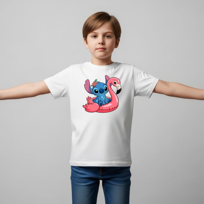 May include: White t-shirt featuring a cartoon illustration of a blue alien character sitting on a pink flamingo float. The alien has a flower in its hair. The flamingo float is in a pool. The t-shirt is worn by a person.