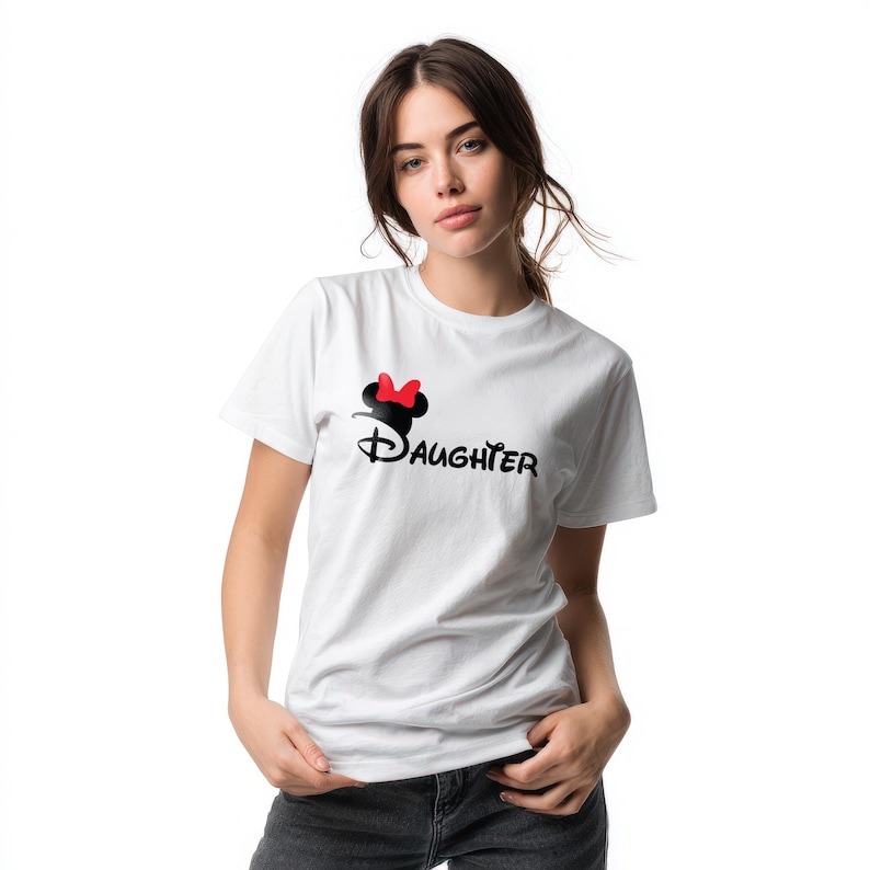 May include: A white short-sleeved t-shirt featuring a black graphic of a mouse ear silhouette with a red bow above the word Daughter written in a stylized black font across the chest area of the garment.