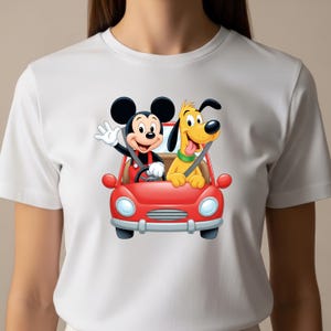 May include: A white short-sleeve t-shirt featuring a graphic print of Mickey Mouse and Pluto riding in a bright red convertible car. Mickey Mouse is in the driver seat waving, while Pluto sits in the passenger seat with a green collar.