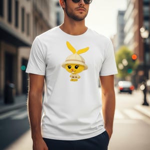 May include: White t-shirt featuring a cartoon yellow bunny wearing a safari hat and outfit. The bunny has long yellow ears and a friendly expression. The shirt is a classic crew neck style.