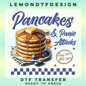 May include: A stack of pancakes with butter and syrup, blueberries, and a jar of syrup. The text "Pancakes & Panic Attacks" is displayed in a whimsical font. The image also includes the text "DTF TRANSFER READY TO PRESS".
