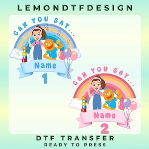 May include: A colorful DTF transfer design featuring a girl, a furry orange character, and a rainbow. The design includes the text "CAN YOU SAY..." and space for a name, with the numbers 1 and 2. The design also includes balloons and the text "DTF TRANSFER READY TO PRESS".