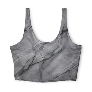May include: A sleeveless crop top featuring a monochromatic gray and black marble stone pattern. The garment has a wide scoop neckline and thick shoulder straps, with visible stitching along the edges and a straight hemline at the bottom.