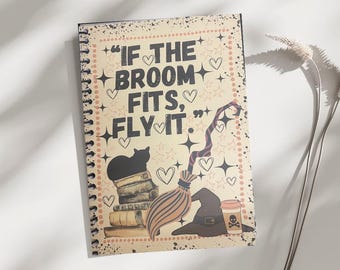 May include: Spiral-bound notebook with a vintage-style design featuring the text "IF THE BROOM FITS, FLY IT." The cover includes illustrations of a black cat, books, a witch's hat, a broom, and a coffee cup with a skull and crossbones.