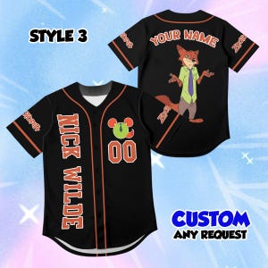 May include: A black baseball jersey with orange trim, featuring the text NICK WILDE, the number 00, and a circular graphic on the front. The back displays the text YOUR NAME and an illustration of a fox character. The sleeves feature Zootopia text.