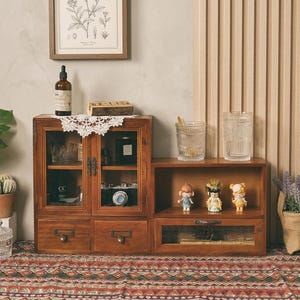 May include: A wooden desktop storage unit featuring a two-door cabinet with glass panels and two lower drawers, paired with an adjacent open-shelf unit containing a single glass-fronted drawer. The set is crafted from medium-toned wood.