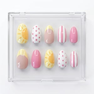 K&ouml;nnte beinhalten: Ein Set aus zehn k&uuml;nstlichen Fingern&auml;geln in einer durchsichtigen Kunststoffbox. Die N&auml;gel zeigen verschiedene Designs, darunter gelbe Sonnen, rosa Punkte, einfarbiges Rosa, vertikale rosa-wei&szlig;e Streifen und ein gelb-rosa French-Tip-Design.