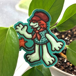 May include: A sticker featuring a cartoon character with a green body, red hair, and a matching cap. The character wears a teal vest and a red scarf. The sticker has a white border and the text "@dazeydayy".
