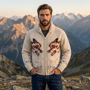 Puede incluir: Suéter con cremallera color crema con cuello chal y dos bolsillos delanteros. El suéter presenta un diseño de punto de dos cabezas de zorro en marrón y negro con detalles en rojo. Patrones de copos de nieve azules en las mangas.