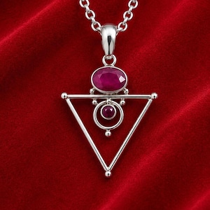 Peut inclure: Un collier pendentif argenté avec un cadre triangulaire géométrique. Le design comprend une grande pierre précieuse ovale rose foncé en haut et une pierre précieuse circulaire rose foncé plus petite centrée dans un anneau argenté.