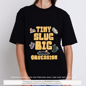 Puede incluir: Una camiseta negra de manga corta con un estampado gráfico que incluye el texto amarillo "TINY SLUG BIG OBSESSION" rodeado de ilustraciones de cinco babosas marinas coloridas en tonos naranja, blanco, azul y verde.