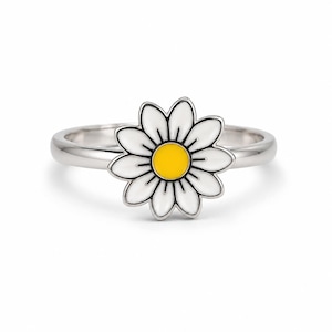 May include: A silver ring featuring a daisy flower design. The flower has white petals, a yellow center, and a black outline. The ring is a simple band with the daisy as the focal point.