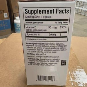 May include: A white rectangular supplement box featuring a Supplement Facts label. The text lists Vitamin D 50 mcg and Apoaequorin 20 mg per capsule. It includes a list of other ingredients, an NSF certification logo, and a barcode at the bottom.