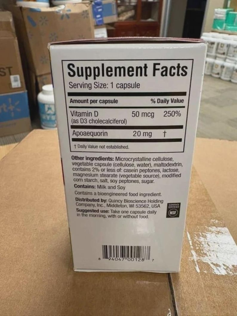 May include: A white rectangular supplement box featuring a Supplement Facts label. The text lists Vitamin D 50 mcg and Apoaequorin 20 mg per capsule. It includes a list of other ingredients, an NSF certification logo, and a barcode at the bottom.
