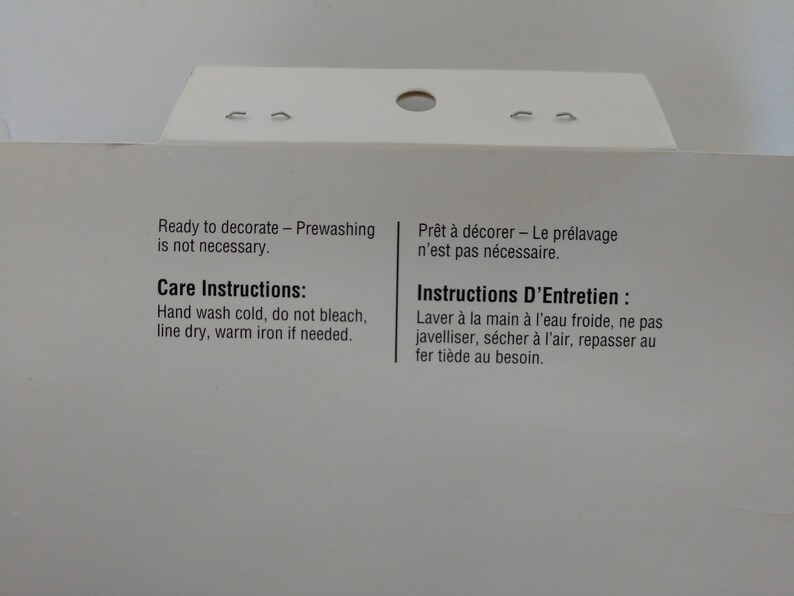 May include: Care instructions for a fabric item.  Ready to decorate - Prewashing is not necessary. Hand wash cold, do not bleach, line dry, warm iron if needed. Pr&ecirc;t &agrave; d&eacute;corer - Le pr&eacute;lavage n'est pas n&eacute;cessaire. Instructions D'Entretien : Laver &agrave; la main &agrave; l'eau froide, ne pas javelliser, s&eacute;cher &agrave; l'air, repasser au fer ti&egrave;de au besoin.