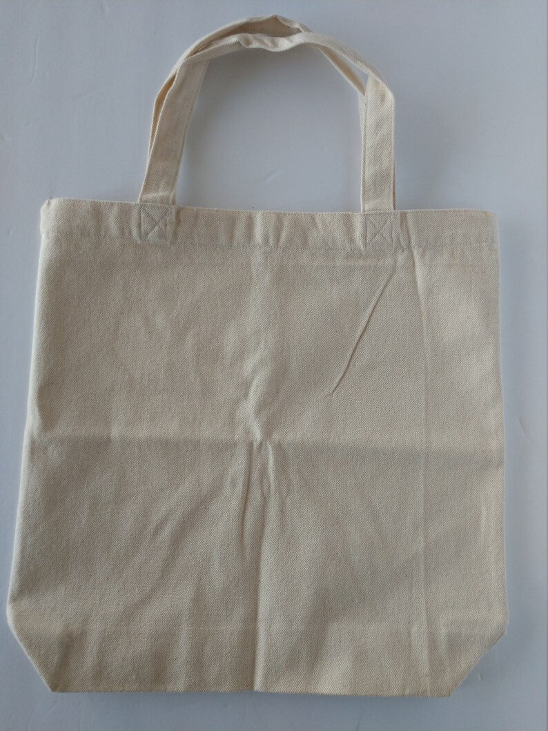May include: A plain, off-white canvas tote bag with two fabric handles.