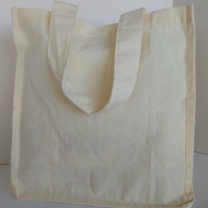 May include: A plain white canvas tote bag with two handles. The bag is made of a soft, natural fabric and has a simple, classic design.
