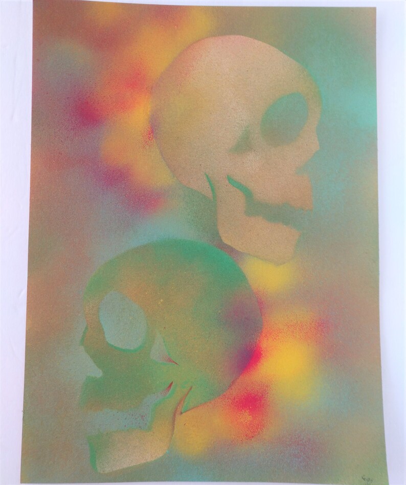 May include: Two skulls painted in a spray paint technique on a canvas background. The top skull is painted in shades of yellow and brown, while the bottom skull is painted in shades of green and blue.