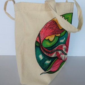 May include: A beige canvas tote bag with a colorful abstract design featuring pink, green, yellow, and blue. The design is of a stylized flower or leaf.