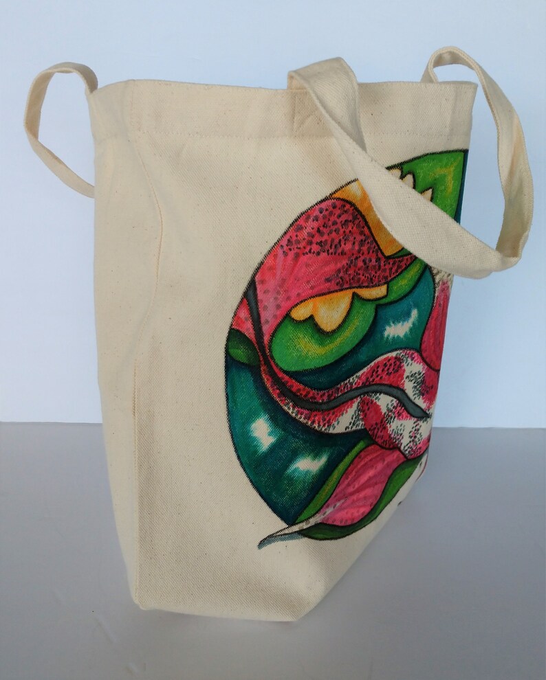 May include: A beige canvas tote bag with a colorful abstract design featuring pink, green, yellow, and blue. The design is of a stylized flower or leaf.